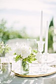 Weisses Blumensträusschen und Kerzen auf Hochzeitstafel im Freien (Ravello, Italien)