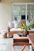 Comfortable veranda with modern coffee table and wicker sofa below window