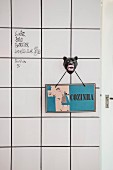 Retro Küchenschild auf einem Haken mit Pantherkopf-Motiv an weisser Fliesenwand