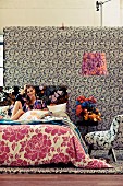 Young woman sitting on bed in room with different patterns