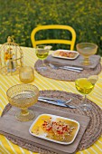 Orange desert for two on yellow and white striped tablecloth and rustic place mats