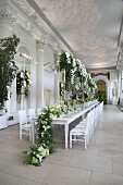 Festliche Hochzeitstafel mit grün-weisser Blumendeko in einem Saal