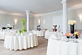 Tables festively set for wedding in room with white columns