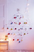 A Christmas tree made of clothes hangers with colourful baubles as wall decoration