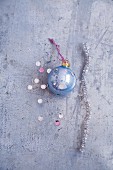 A pipe cleaner, light-blue Christmas bauble and glitter confetti