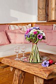Free-standing bouquet of anemones stood in dish on rustic, solid wooden table