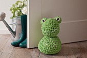 Crocheted frog doorstop on wooden floor