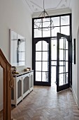 Eleganter Eingangsbereich einer Villa, Flügeltür aus Holz und Glas, moderne Pendelleuchte an Stuckdecke