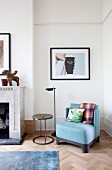 Blue easy chair and metal side table below framed photographic artwork on wall in corner