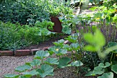 Gemüsebeeteinfassung mit Ziegelsteinen und Metallschild mit Katzenmotiv im sommerlichen Bauerngarten