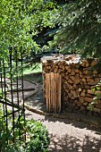 Firewood stacked next to curved gravel path in garden