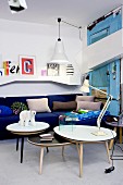 Set of coffee tables in front of royal-blue couch and white wall-mounted shelves in eclectic interior