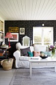 Sofa, white coffee table and wall covered in black and white wallpaper in romantic Swedish cabin
