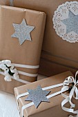 Christmas presents wrapped in brown paper decorated with silver stars and paper doilies