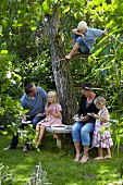 Familie isst Kuchen unter einem Baum im Garten