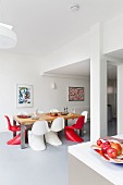 Red and white classic chairs around table in dining area in bright, open-plan interior