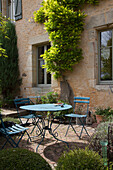 Terrassenplatz mit blauem Tisch und Klappstühlen vor französischem Herrenhaus