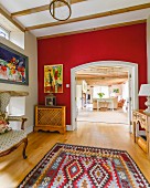 Ethnic rug, red wall and open doorway with view into open-plan interior