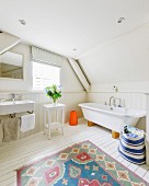 Colourful rug on white wooden floor in rustic wood-clad bathroom