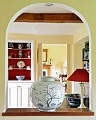 Exquisite vase on sill of arched interior aperture with view of dresser next to open door