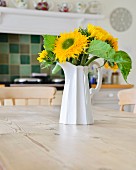 White jug of sunflowers on wooden table in country-house kitchen