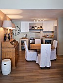 Comfortable country-house kitchen with white loose-covered chairs and plain wooden furniture