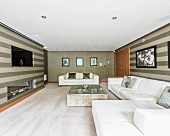 White leather sofa, stripes wallpaper and gas fireplace in luxurious interior