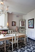 Esszimmer mit langem Holztisch und Stühlen, antikem Vitrinenkschrank und Künstlerambiente