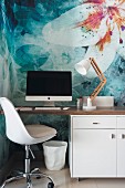 Retro swivel chair at modern desk against wall with floral motif