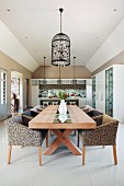 Leopard-print armchairs at long wooden table below pendant lamp with bird-cage lampshade in open-plan interior