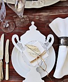 White place setting with vintage-style paper decoration on wooden table
