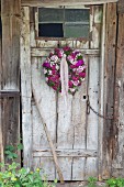 Blumenkranz aus Bartnelken an rustikaler Holzbrettertür