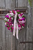 Wreath of pink Sweet Williams hung on rustic board door