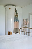 Summer dress hung on antique, white, cylindrical tiled stove