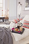 A breakfast tray with coffee and pastries on a double bed