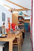 Long desk, several chairs and collections of curiosities in loft apartment