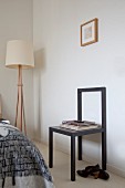 Minimalistischer, schwarzer Stuhl an Wand und Stehleuchte in Zimmerecke