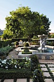 Landscaped garden with fountain, stone sculpture, clipped hedged and paved paths