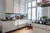 Fitted kitchen with white doors and herringbone parquet floor in period apartment