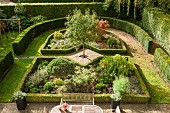 View down onto elegant garden with herbaceous borders surrounded by clipped hedges