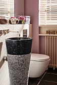 Conical stone pedestal sink with wall-mounted tap in modern bathroom