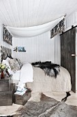 Bed with canopy and fur blanket in cosy bedroom