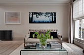 Elegant button-tufted sofa, plexiglas coffee table and pictures on wall in living room