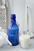 Still-life arrangement of blue milk bottle and full glass of milk
