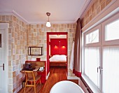 Kleiner Tisch im Bad Ensuite neben Durchgang zu Schlafzimmer mit roter Wand