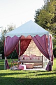 Shady seating area in garden in style of Bedouin tent with draped purple curtains