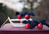 Deko-Schlitten mit roten Äpfeln und dunkelblauen Schleifen