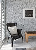 Armchair and designer bedroom bench on marble tiles and against patterned wallpaper