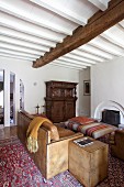 Traditionelles Wohnzimmer mit hellbrauner Ledercouch, Beistelltisch und Polstertisch vor offenem Kamin, weiße Holzbalkendecke