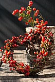 Small wreath of rose hips on wooden table